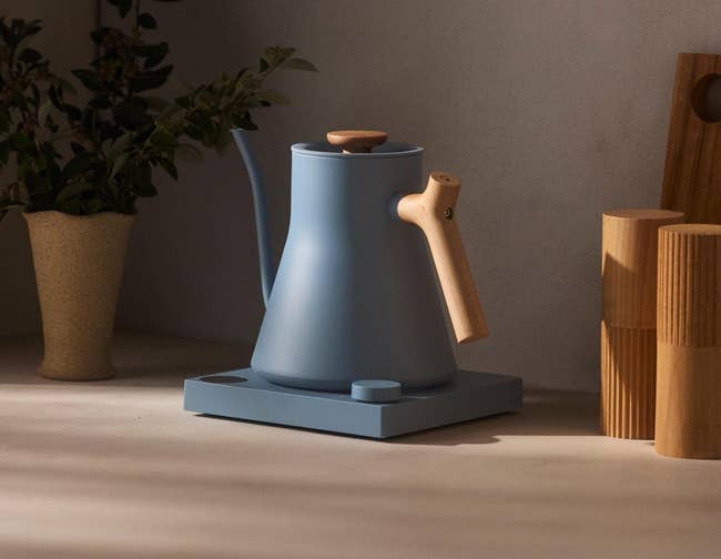 Stylish pour-over kettle with a woody grip connected a countertop, adjacent to minimalist decor; substance highlights its plan focus