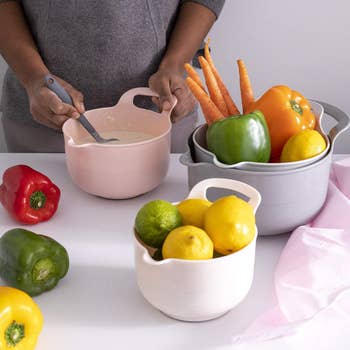 four different sized bowls with handles and spouts in light pink to grey