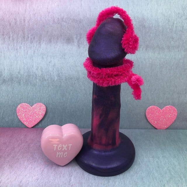 Purple dildo next to conversation heart with pipecleaners
