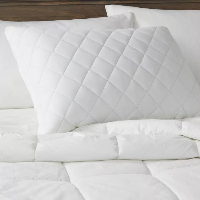 White quilt-patterned pillow on a bed, showcasing a style for home bedding accessories