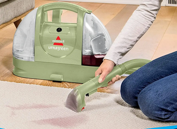person using Little Green machine to clean stain on carpet