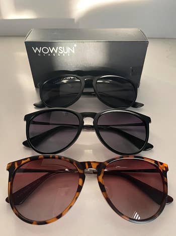 Three pairs of sunglasses successful  antithetic  styles, with a container  labeled 