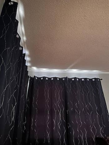 Dark curtains with wavy patterns bent from a ceiling, blocking airy and creating a cozy atmosphere