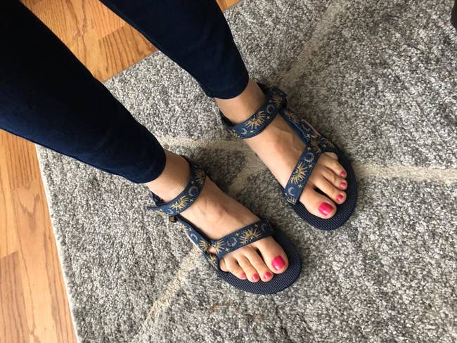 a reviewer wearing tevas strappy sandals with a moon and sun pattern on them
