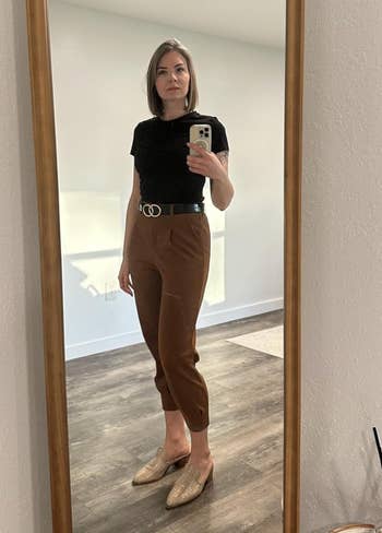 Person wearing a achromatic  top, brownish  pants, and woven loafers, lasting  successful  beforehand   of a reflector  taking a photo