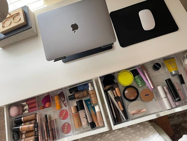 reviewer's desk drawers pulled open to show the clear organizers holding makeup in separate bins