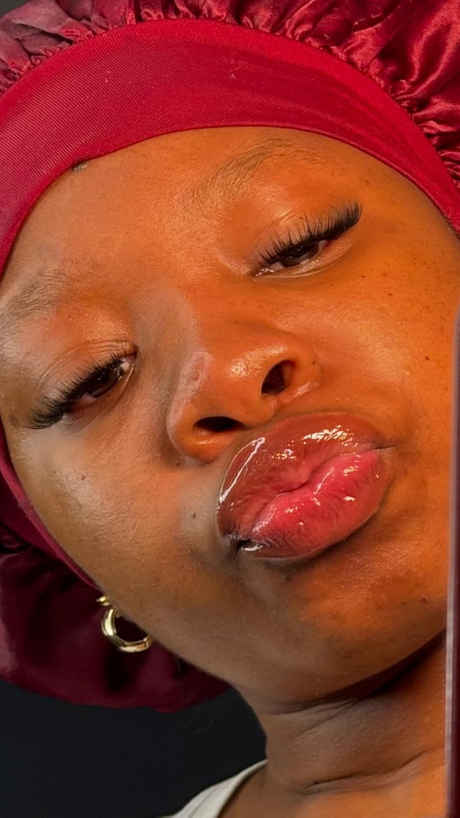 Person wearing a satin bonnet and earrings, pouting for a close-up selfie