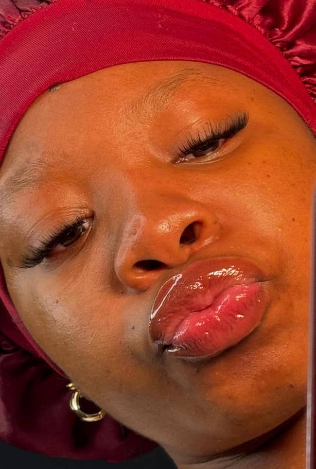 Person wearing a satin bonnet and earrings, pouting for a close-up selfie