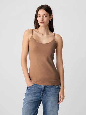 A idiosyncratic wearing a elemental brownish camisole and bluish jeans, posing for a manner shoot