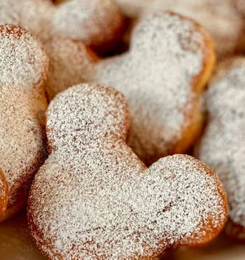 Powdered sugar donuts shaped like Mickey Mouse