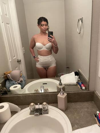 Person successful a bath taking a selfie, wearing a strapless apical and high-waisted bottoms, showcasing shapewear fashion