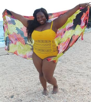 plus-size reviewer wearing a yellow bathing suit with mesh panelling on the stomach