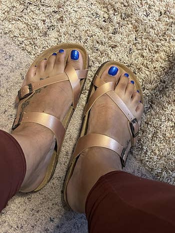 Person wearing brown sandals and blue toenail polish