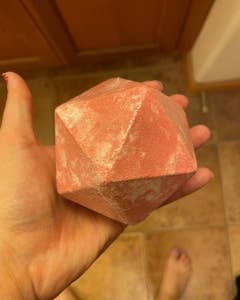 a reviewer holding a large D20-shaped bath bomb 