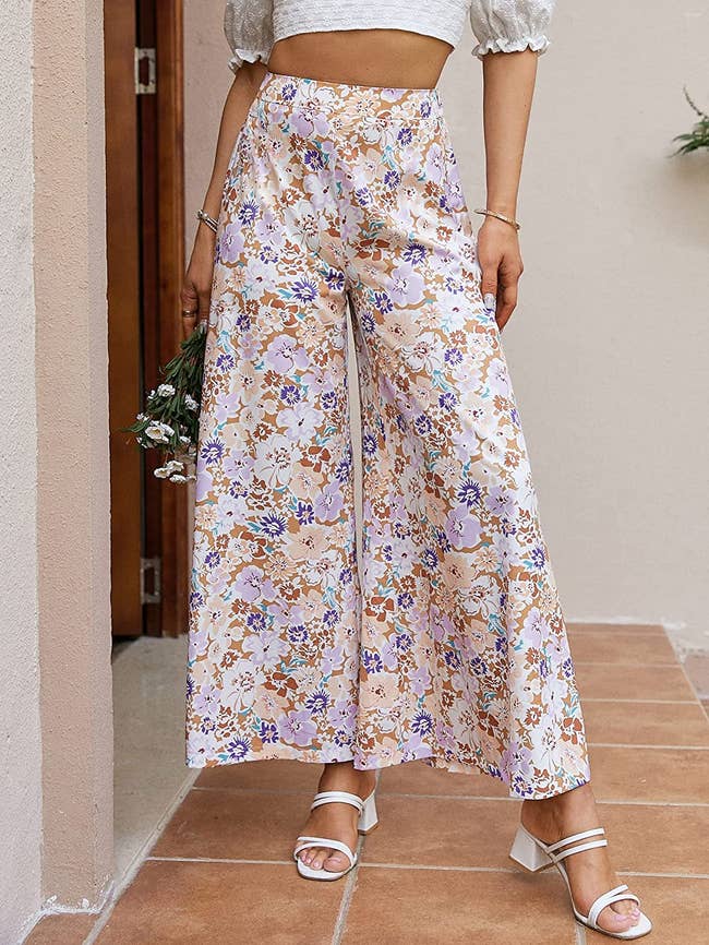 model in pink, purple, and red floral-print high-rise palazzo pants and white sandals
