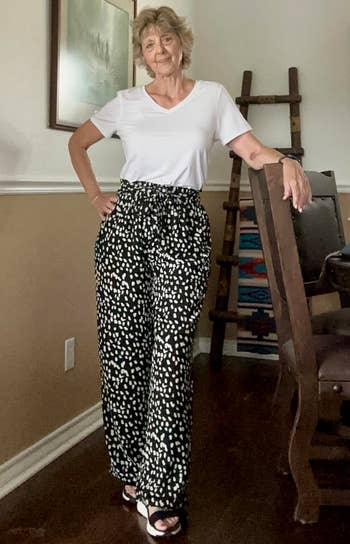 Person successful a casual achromatic apical and patterned high-waisted pants stands confidently indoors, suggesting a relaxed yet stylish look for shopping