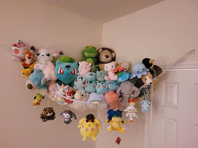 a reviewer. photo of one of the hammocks hung in the corner of a room and loaded up with stuffed animals 