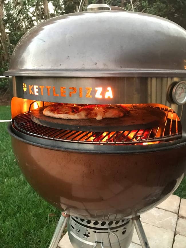 reviewer photo of the steel insert over a round grill and a pizza cooking inside