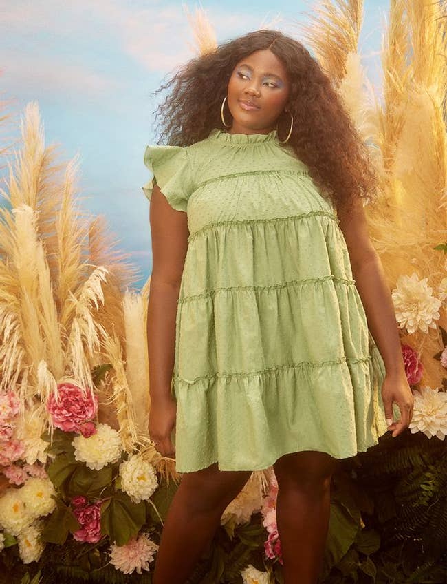 a model wearing the tiered dress with ruffle sleeves in the color green