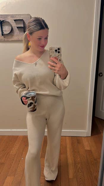 Person taking a reflector  selfie wearing a cozy knit lounge set, holding a patterned mug, with a modern   woody  partition  decoration successful  the background