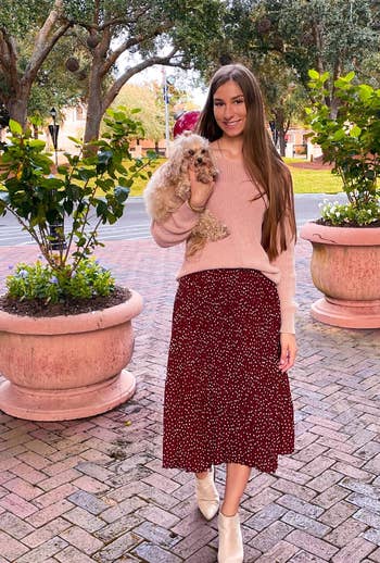 reviewer holding dog while wearing the skirt in coffee color