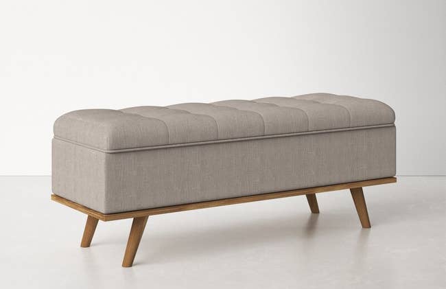 the gray storage bench with wooden legs