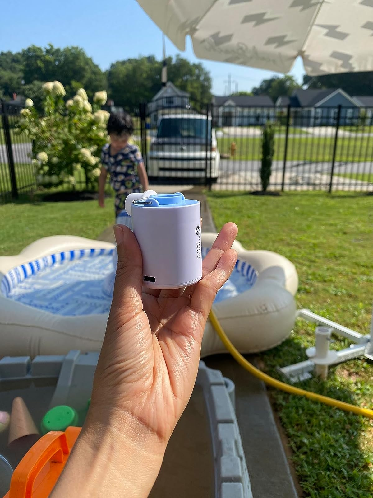reviewer holding a tiny  electrical  aerial  pump adjacent   an inflatable pool