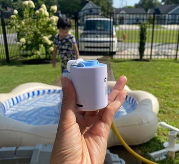 reviewer holding a tiny electrical aerial pump adjacent an inflatable pool
