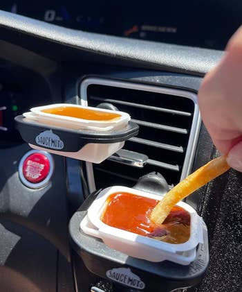 image of reviewer dipping a fry into sauce sitting inside a black dip clip in a car