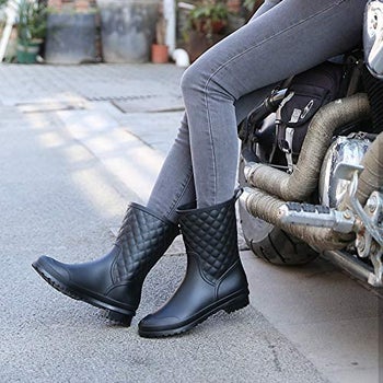 a model in black rain boots with quilted pattern