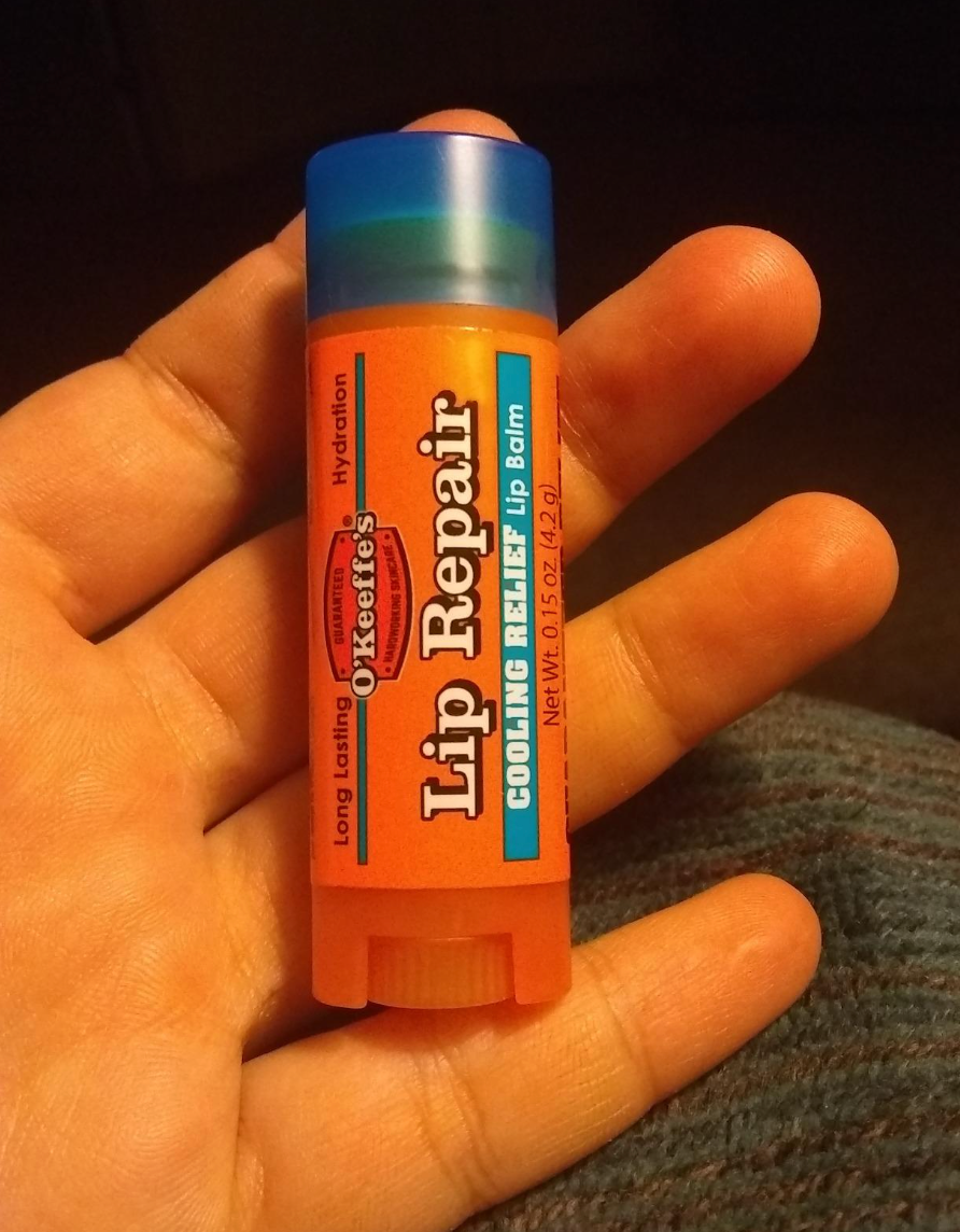 A reviewer holding the lip balm
