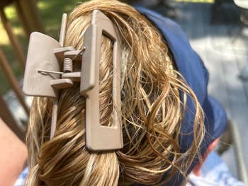 Close-up of a hairsbreadth  claw clip holding damp, styled hair. Person wears a headband, suggesting a casual, applicable  hairstyle for mundane  wear
