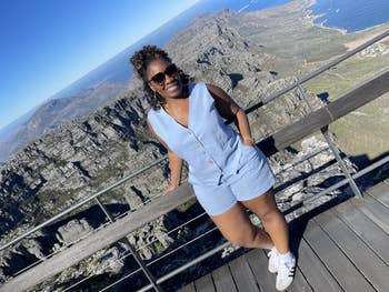 Person successful  sleeveless button-up garment  and shorts, lasting  connected  a upland  lookout, wearing sunglasses and sneakers, with scenic vista successful  the background