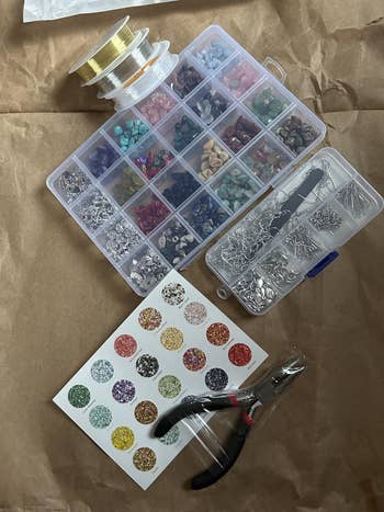 Jewelry-making kit with beads, tools, and stringing materials, placed on a textured surface
