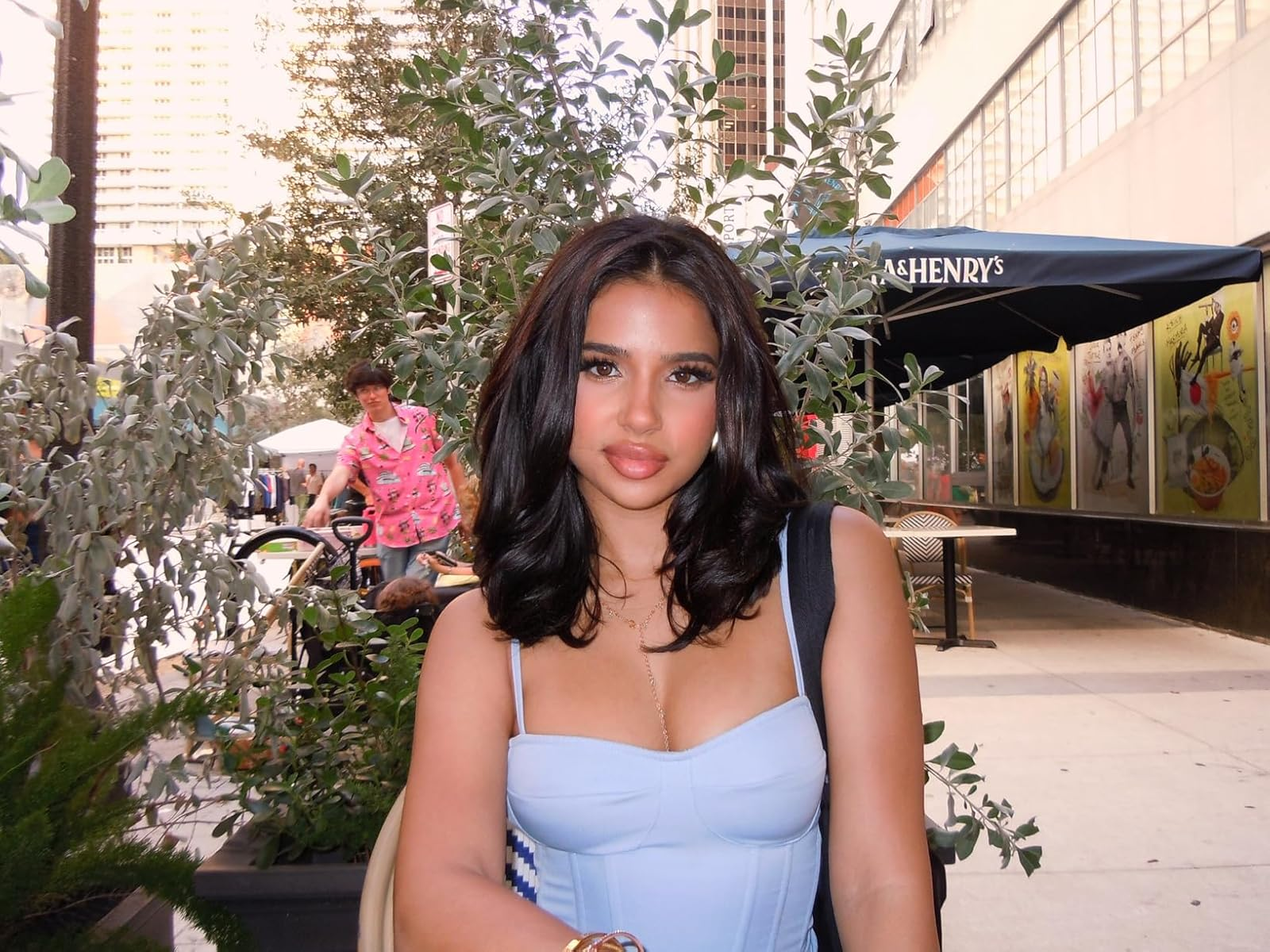 Person sitting outdoors successful  a metropolis  country   wearing a stylish outfit. Urban backdrop with trees and a cafe