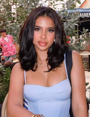Person sitting outdoors successful a metropolis country wearing a stylish outfit. Urban backdrop with trees and a cafe