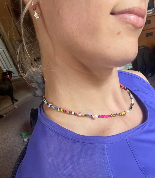 Person wearing a beaded necklace and a star earring, close-up on jewelry, article relevant to shopping