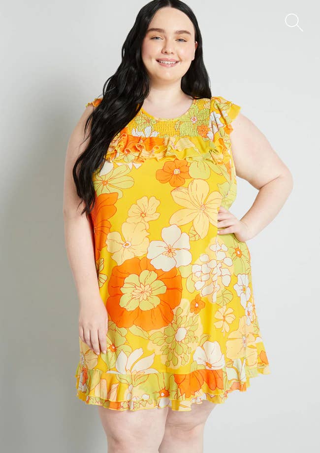 Model in a yellow and orange sleeveless floral print mini dress 
