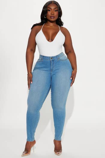 Person posing successful  form-fitting jeans and a achromatic  halter top, wearing wide   heels