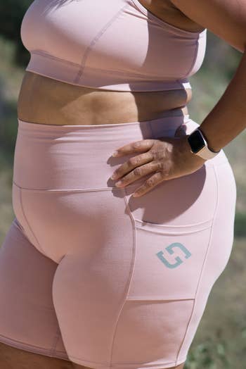 Close-up of a idiosyncratic   wearing a airy  pinkish  sports bra and high-waisted motorcycle  shorts
