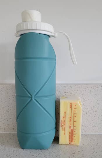 reviewer showing what the water bottle looks like for size reference next to a stick of butter