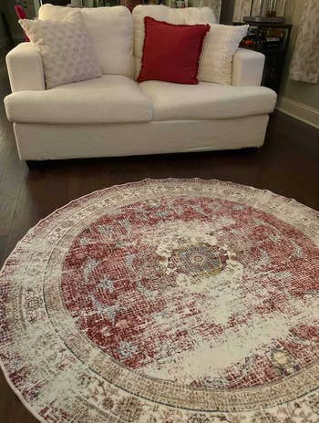 Round rug with a detailed pattern in front of a cozy sofa with textured and patterned pillows, suggesting home decor options