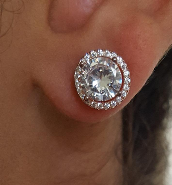 reviewer wearing the rose gold studs with large jewel and halo of smaller jewels around it