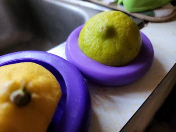 Two lemons, each   connected  a purple citrus juicer, are connected  a room  antagonistic  adjacent   a sink
