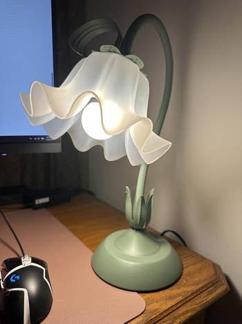 Floral-shaped table  lamp with a curved basal   adjacent  to a machine  rodent  connected  a woody  surface