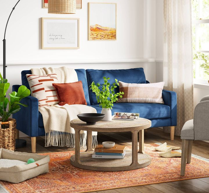 a blue velvety sofa with throw pillows and blankets on it