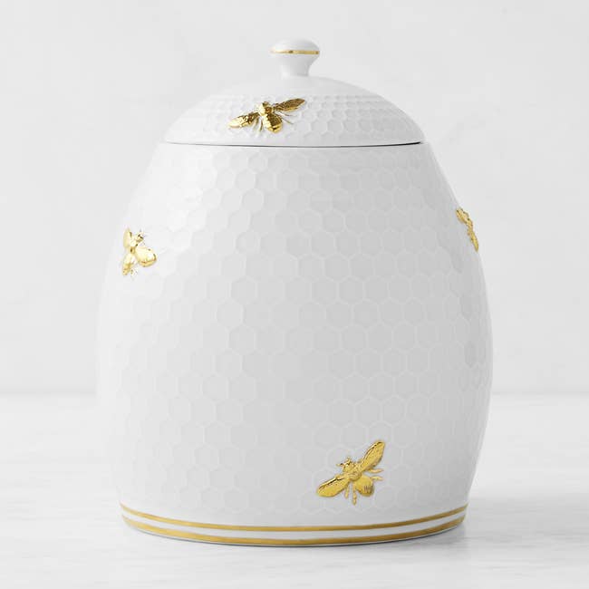 a white honey comb cookie jar with golden bee accents