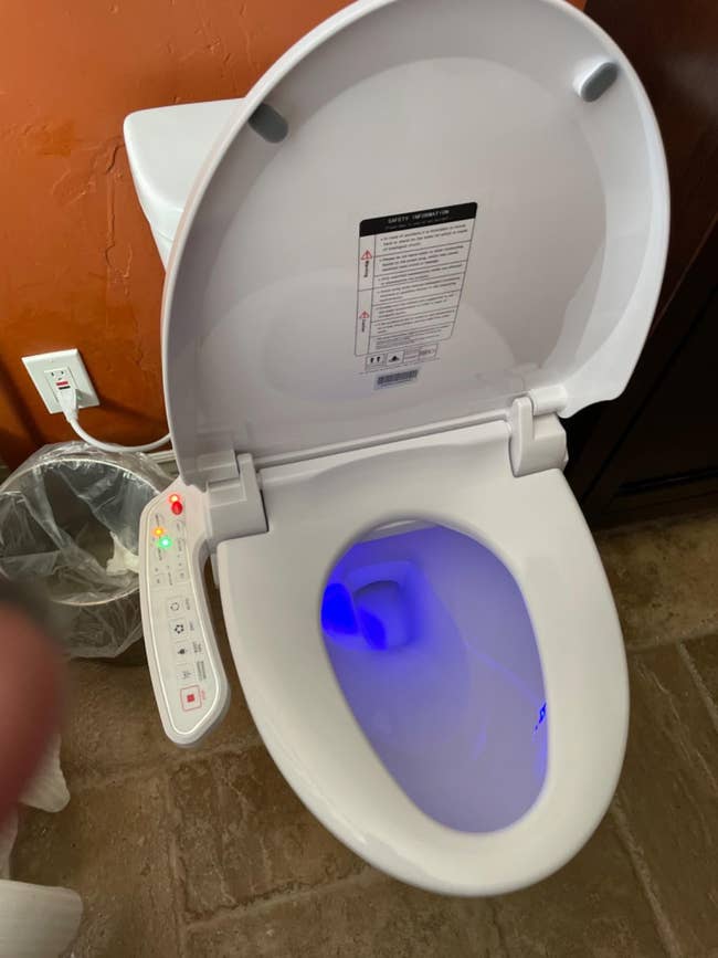 High-tech toilet with bidet features and remote control, soft lighting inside bowl
