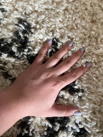 buzzfeed editor placing their hand on the rug to show the long pile length