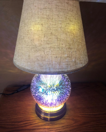 a reviewer photo of the same lamp turned on with the based featuring a dimensional light effect 